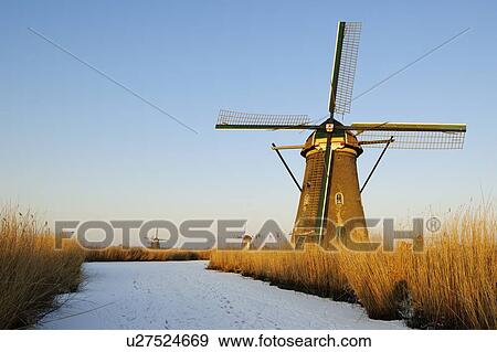 Windmill by river in rural landscape View Large Photo Image Stock Photo - Windmill by river in rural landscape. Fotosearch