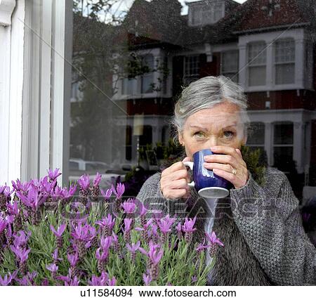 Woman drinking coffee at window View Large Photo Image Picture - Woman drinking coffee at window. Fotosearch