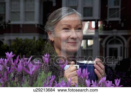 Picture - Woman drinking coffee at window. Fotosearch