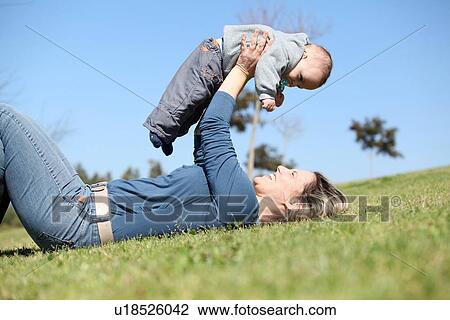 Woman playing with baby in grass View Large Photo Image Stock Image - Woman playing with baby in grass. Fotosearch