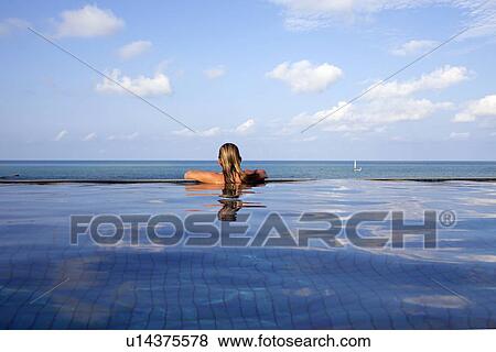 Stock Photo - Woman relaxing in infinity pool. Fotosearch