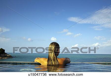 Stock Photograph - Woman relaxing in infinity pool. Fotosearch