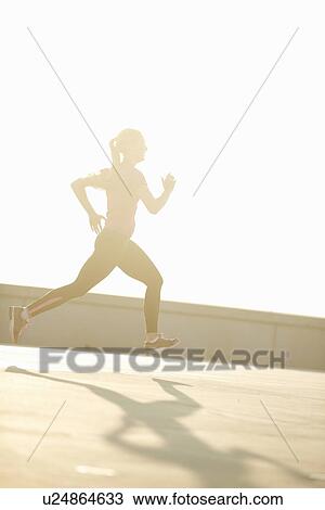 Stock Image - Woman running on rooftop. Fotosearch