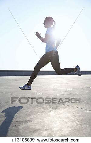 Woman running on rooftop View Large Photo Image Stock Photo - Woman running on rooftop. Fotosearch