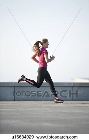 Woman running on rooftop View Large Photo Image Stock Photo - Woman running on rooftop. Fotosearch