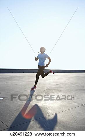 Stock Photo - Woman running on rooftop. Fotosearch
