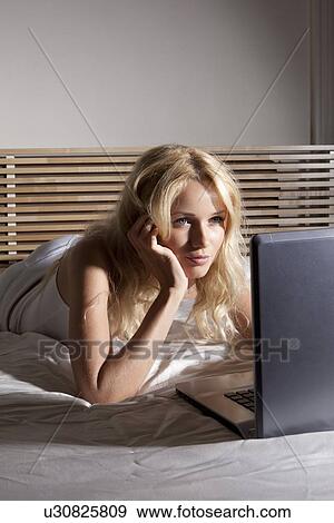 Stock Photo - Woman using laptop on bed. Fotosearch