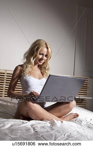 Stock Photograph - Woman using laptop on bed. Fotosearch
