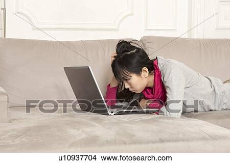Woman using laptop on couch View Large Photo Image Picture - Woman using laptop on couch. Fotosearch