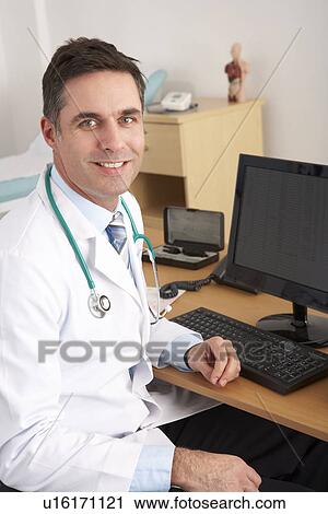 Stock Image - American doctor sitting at desk. Fotosearch