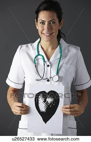 Stock Image - American nurse holding ink drawing of heart. Fotosearch