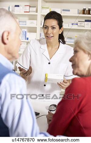 Stock Image - American pharmacist dispensing to senior couple. Fotosearch