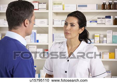 Stock Image - American pharmacist talking to man in pharmacy. Fotosearch