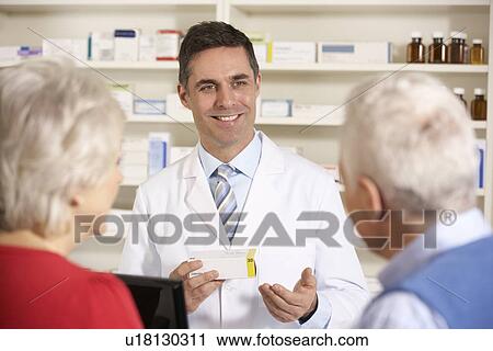 Stock Image - American pharmacist with senior couple in pharmacy. Fotosearch