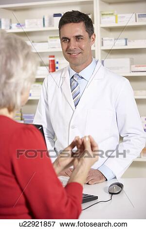 Stock Photo - American pharmacist with senior woman in pharmacy. Fotosearch