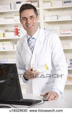 Stock Image - American pharmacist working on computer. Fotosearch