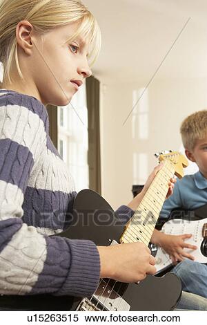 Stock Photography - Boy and girl playing electric guitars at home. Fotosearch