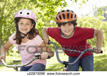 Stock Photograph - Boy and girl riding bikes. Fotosearch