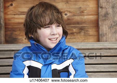 Stock Photo - Boy Dressed For Cold Weather Sitting On Wooden Bench. Fotosearch