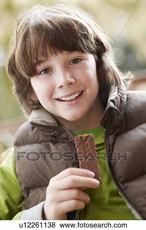 Stock Photo - Boy Eating Chocolate Bar Wearing Winter Clothes. Fotosearch