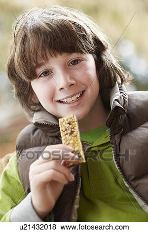 Stock Photo - Boy Eating Healthy Snack Bar Wearing Winter Clothes. Fotosearch