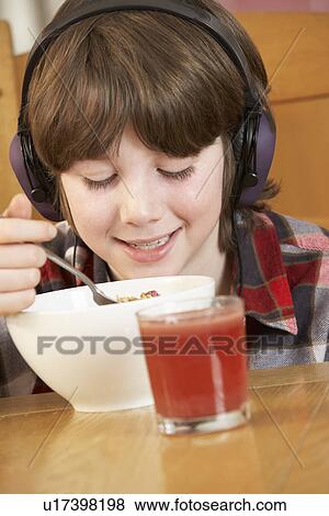 Stock Photo - Boy Listening To MP3 Player Whilst Eating Breakfast. Fotosearch