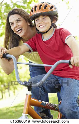 Stock Photo - Boy on bike with mother. Fotosearch