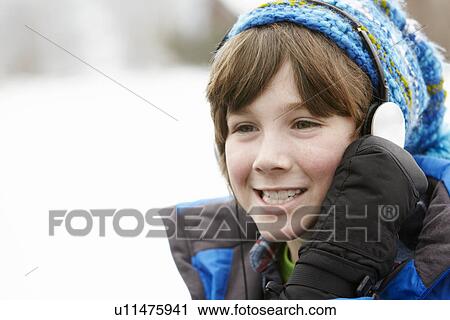 Stock Image - Boy Wearing Headphones And Listening To Music Wearing Winter Clothes In Snowy Landscape. Fotosearch