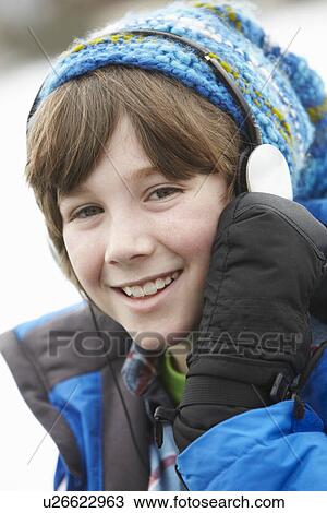 Stock Image - Boy Wearing Headphones And Listening To Music Wearing Winter Clothes In Snowy Landscape. Fotosearch