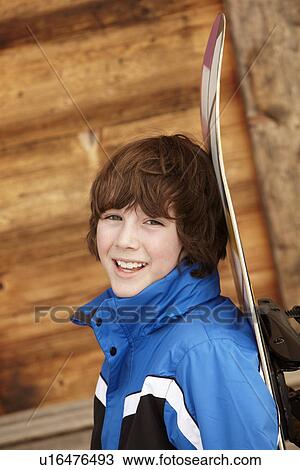 Stock Image - Boy With Snowboard On Ski Holiday In Front Of Wooden Background. Fotosearch