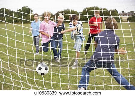 Stock Photo - Boys playing soccer in park. Fotosearch
