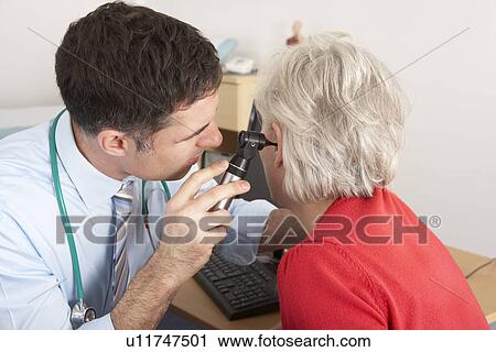 Stock Image - British doctor examining senior woman's ear. Fotosearch