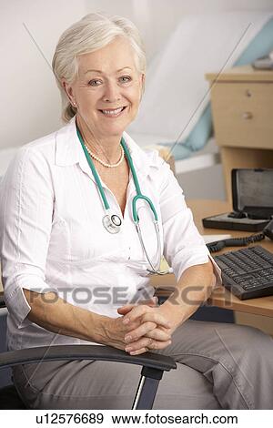 Stock Photo - British female GP sitting at desk. Fotosearch