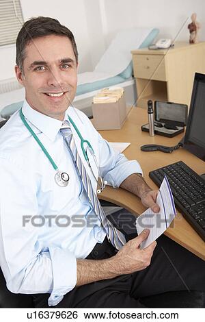 Stock Photograph - British male GP sitting at desk. Fotosearch