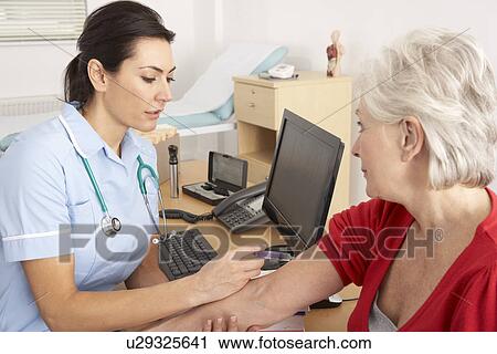 Stock Image - British nurse giving injection to senior woman. Fotosearch