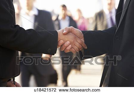 Stock Image - Businessman and business woman shaking hands in street. Fotosearch