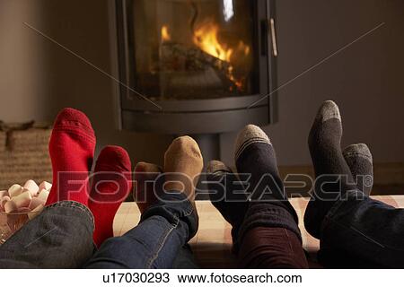 Stock Image - Close Up Of Familys Feet Relaxing By Cosy Log Fire With Marshmallows. Fotosearch