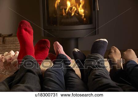 Stock Image - Close Up Of Familys Feet Relaxing By Cosy Log Fire With Marshmallows. Fotosearch