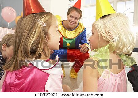 Stock Image - Clown entertaining children at party. Fotosearch