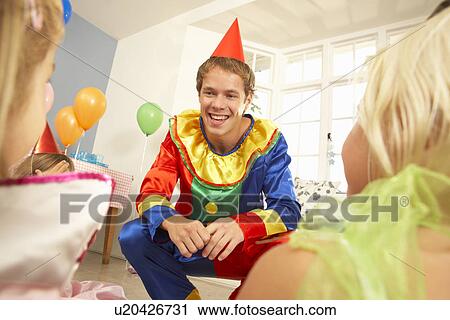 Stock Image - Clown entertaining children at party. Fotosearch