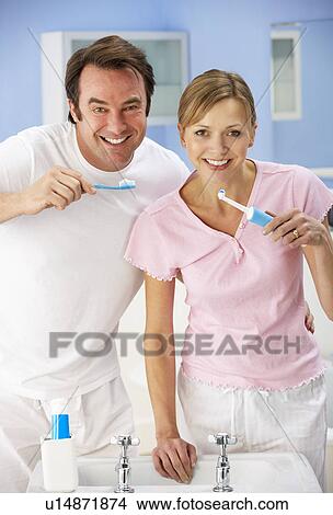 Couple cleaning teeth together in bathroom View Large Photo Image Picture - Couple cleaning teeth together in bathroom. Fotosearch