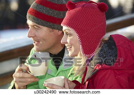 Stock Image - Couple Enjoying Hot Drink In CafÃ© At Ski Resort. Fotosearch