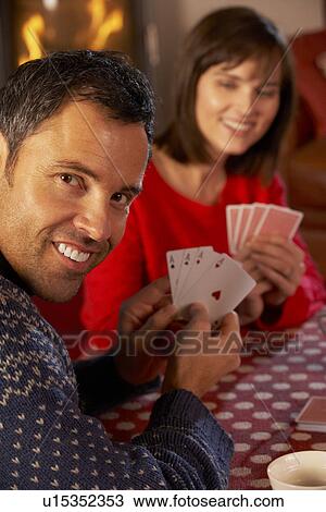 Stock Image - Couple Playing Cards By Cosy Log Fire. Fotosearch