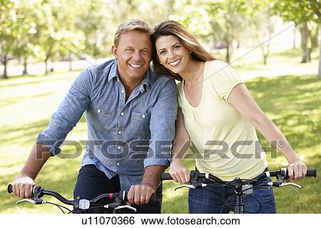 Stock Photograph - Couple riding bikes in park. Fotosearch
