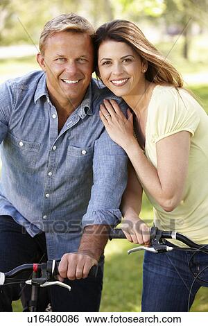 Stock Photograph - Couple riding bikes in park. Fotosearch