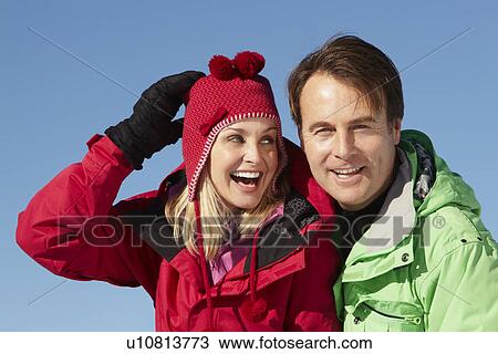 Couple Standing In Snow Wearing Warm Clothes On Ski Holiday In Mountains View Large Photo Image Stock Image - Couple Standing In Snow Wearing Warm Clothes On Ski Holiday In Mountains. Fotosearch