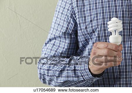 Stock Photo - Cropped Studio Shot Of Man Holding Energy Saving Lightbulb. Fotosearch