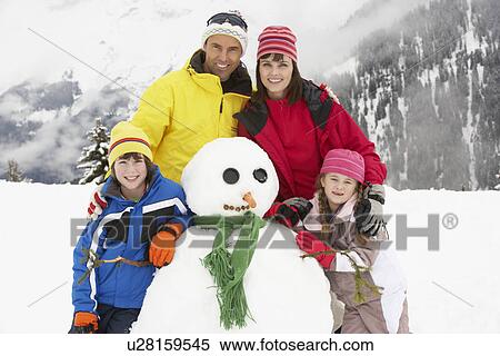 Stock Photography - Family Building Snowman On Ski Holiday In Mountains. Fotosearch