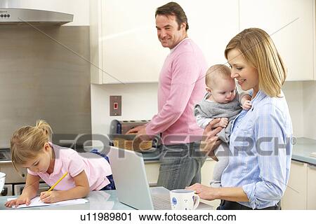Stock Image - Family busy together in kitchen. Fotosearch