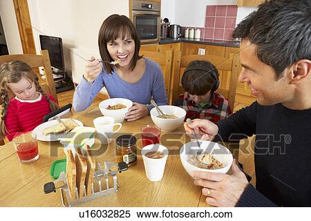 Stock Photography - Family Eating Breakfast Together In Kitchen Whilst Children Play With Gadgets. Fotosearch